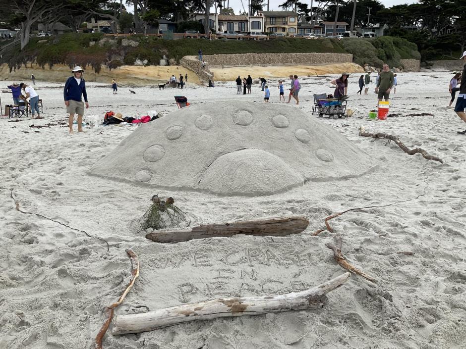 Sand sculpture of a UFO and kelp aliens landing